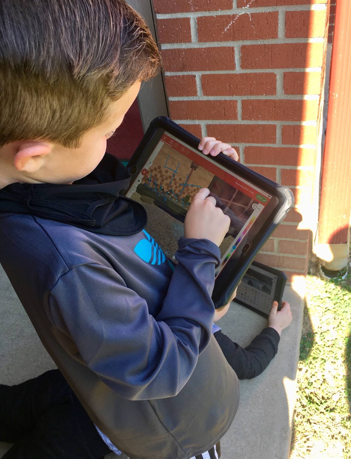 Boy using his ipad for an assignment while outdoors